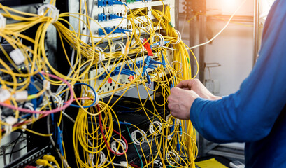 Network engineer working in server room. Connecting network cables to switches