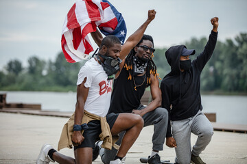Fototapeta na wymiar Three protestors kneeling while holding American flag