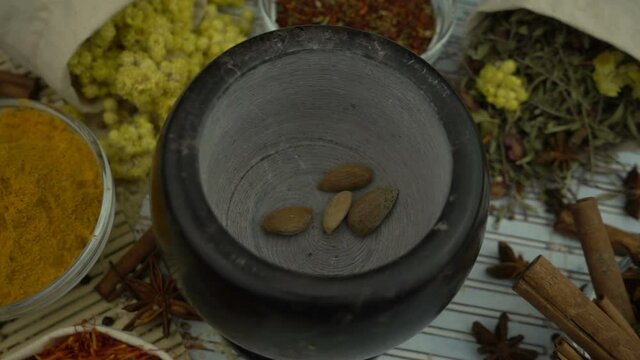 Almonds seeds falling into the granite mortar in slow motion. Healthy and organic food, herb medicine, natural care, aromatherapy and organic cosmetics concept.