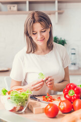 Woman cutting vegetables on salad on kitchen.
