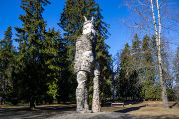 High sculpture giant with a tub, against the background of the forest and blue sky