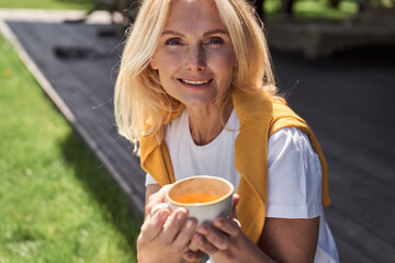 Happy woman with cup of coffee on sunny day - Powered by Adobe