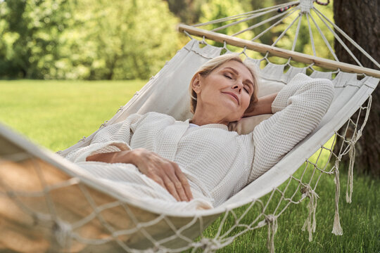 Happy mature female sleeping in hammock outdoors