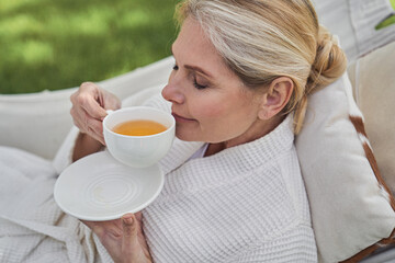 Serene female having cup of hot drink outdoors