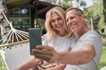 Merry spouses taking selfie in green yard