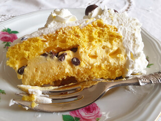 A piece of cake with cream and coffee beans on a vintage plate with a fork.