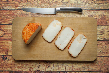 Goat cheese cut on wooden board with knife