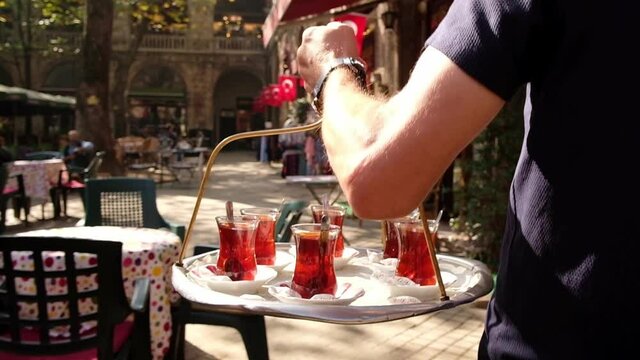 Waiter delivering traditional Turkish tea on a tray