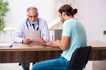 Obraz premium Injured young man visiting old doctor