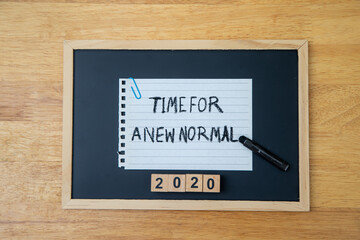 Obraz premium Conceptual hand writing showing Time For A New Normal, on white paperclip hold written chalkboard on wooden deck.