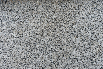 Rough gray concrete wall with black stones. Modern plaster