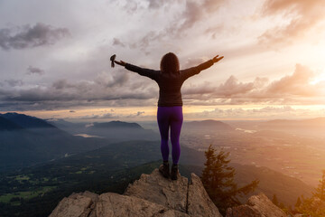 Fototapeta na wymiar Adventurous Girl on top of a Rocky Mountain overlooking the beautiful Canadian Nature Landscape during a dramatic Sunset. Taken in Chilliwack, East of Vancouver, British Columbia, Canada. Bird Flying