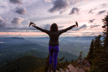Adventurous Girl on top of a Rocky Mountain overlooking the beautiful Canadian Nature Landscape during a dramatic Sunset. Taken in Chilliwack, East of Vancouver, British Columbia, Canada. Bird on Hand