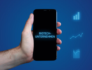 Biotech-Unternehmen. Hand hält Telefon (Handy). Wort auf Display. Diagramme auf Hintergrund blau. Business