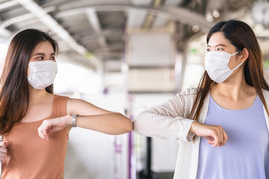 Young Asian woman passenger wearing surgical mask and elbows bump with friend together in subway train when traveling in big city at Covid19 outbreak, Infection and Pandemic, new normal concept