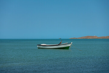 Naklejka na ściany i meble Lonely traditional Colombian fishing boat on sea water with clear water and blue sky - at Cabo de la vela, La guajira, Colombia
