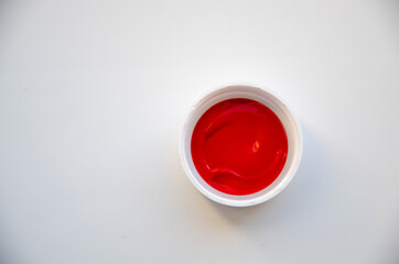 Fototapeta na wymiar A cup with red acrylic paint on the white background