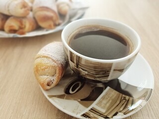 cup of black coffee and homemade croissant close up