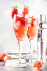 Rossini italian red alcoholic cocktail with sparkling wine, strawberry puree and ice in champagne glasses, copy space