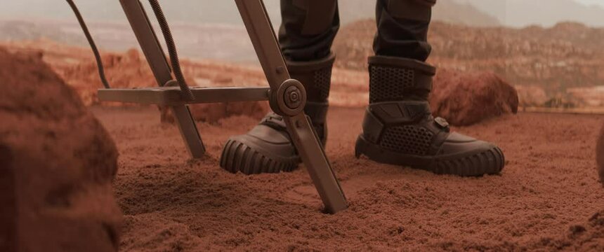 Astronaut getting down to a surface of a red planet from a spaceship, making first steps. Mars colonization concept.