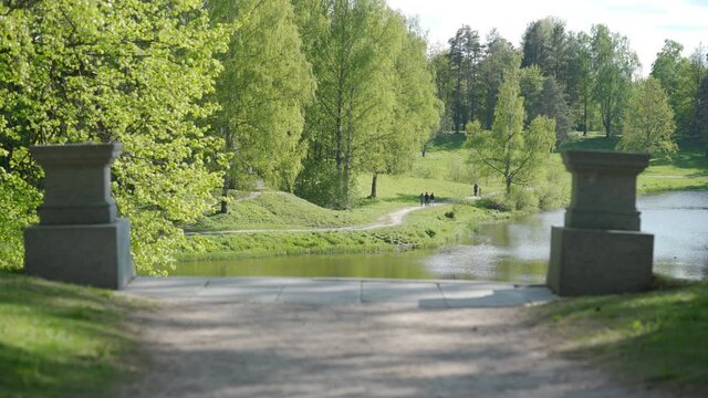 Empty footpath in park on sunny spring day to Marienthal pond and staircase in Pavlovsk, Saint Petersburg, Russia.