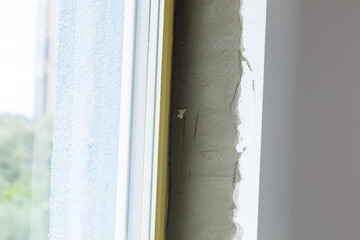 Repair in the slopes of the window. The process of applying a layer of plaster on the sides of the...