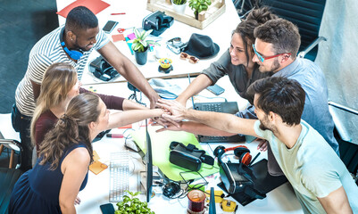 Young employee startup workers group stacking hands at urban studio during entrepreneurship...