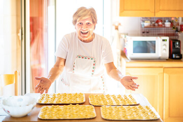 Happy woman presenting handmade " cappelletti " at house kitchen - Local food concept with home made italian pasta preparation - Warm bright backlight filter