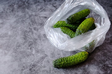 Spoiled cucumbers are in a plastic bag on a dark background. Concept. Polluting to store vegetables in these packets. Copy space.