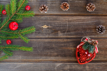 New year flat lay: Christmas green spruce branch of new year tree with red apples, cones, toy heart on a rustic wooden background