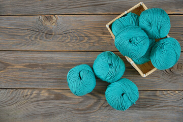 Colored Balls of Yarn For Knitting Lie in a Wicker Basket On Wooden Background Top View