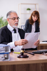 Old male judge and his young secretary in the office