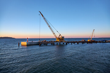 Port crane bridge and bulk carrier at sunset.