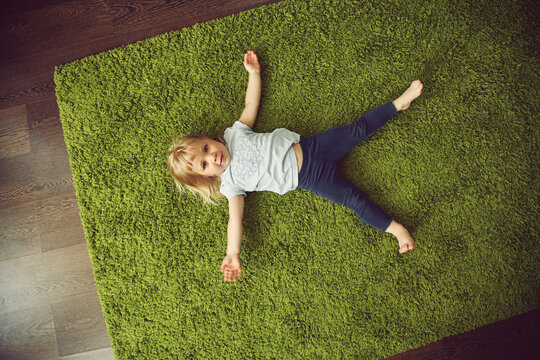 funny little girl lying on a carpet. child playing at home.