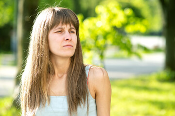 Naklejka premium Portrait of serious pretty young woman in summer park.