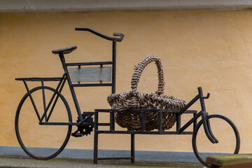 Classic bicycle standing next to the wall. Bicycle leaned on the wall. Basket on the bicycle.