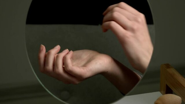 Reflection of female hands with perfume in mirror