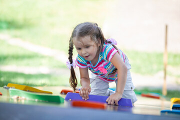 Beautiful little girl climbs up the climbing wall, active games and recreation, children's street...