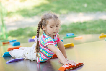 Beautiful little girl climbs up the climbing wall, active games and recreation, children's street...