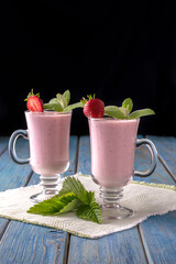 strawberry yogurt in a glass cup on a blue wooden table.
