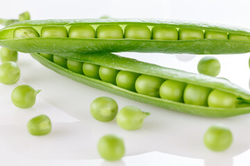 Pods of green peas with pea leaves and flowersd on a white background. Organic food.