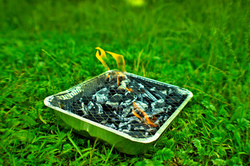 Rozpalający się grill jednorazowy na trawie z płomieniem.