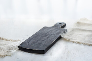 Fototapeta premium Empty vintage cutting board on white wooden table with linen napkins.