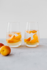 Fruit water with ice and slices of apricots and peaches on a light background. 