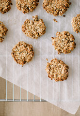 Oatmeal cookies on white parchment and itch are cooled after the oven. View from above