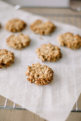 Recipe for homemade oatmeal cookies. Pieces are laid out on parchment paper and a grate.