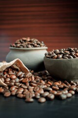 Coffee beans in an earthenware dish and a bag on a wooden table.