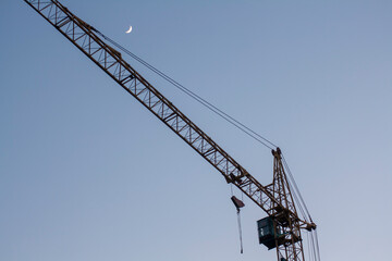 Fototapeta na wymiar Crane at sunrise against the background of the moon
