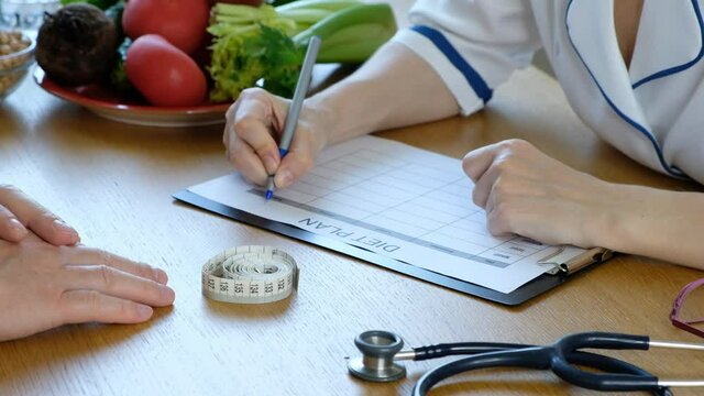 Doctor nutritionist consulting patient and writing diet nutrition plan, close up