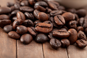 Closeup shot of brown roasted coffee beans on wooden table.